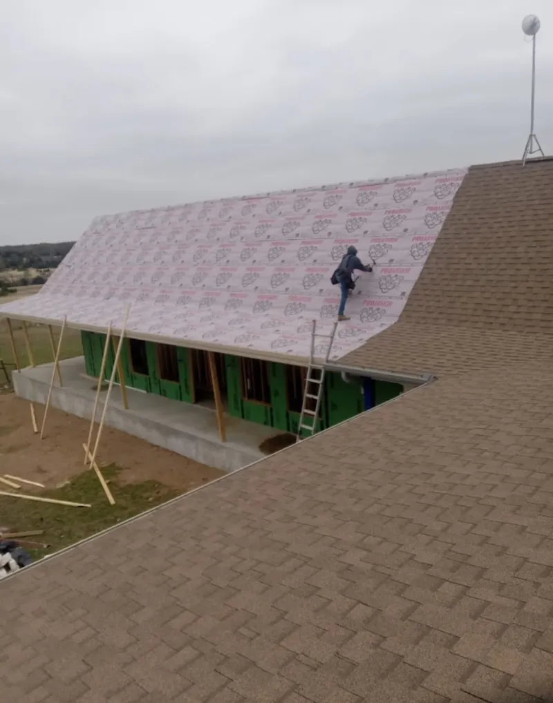 Worker preparing underlayment for a metal roof installation in Edmond